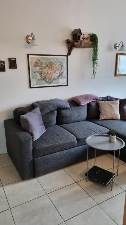 Notaleg setustofa með þægilegum sófa og listrænum kortum af Íslandi.